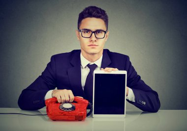 Masa başında oturan eski moda telefon ve modern tablet ile ciddi iş adamı