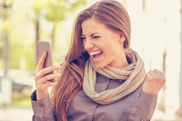 Estudiante emocionado leyendo buenas noticias en el teléfono móvil al aire libre en un cálido día de otoño — Foto de Stock