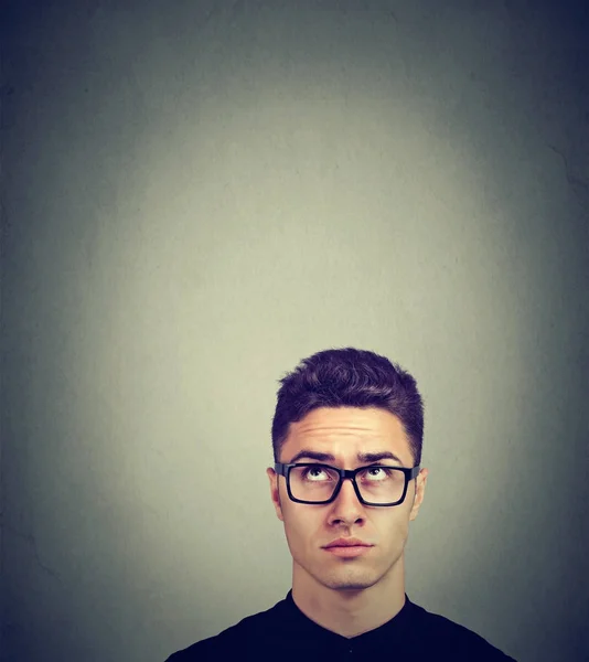 Joven dudoso en gafas mirando hacia arriba — Foto de Stock