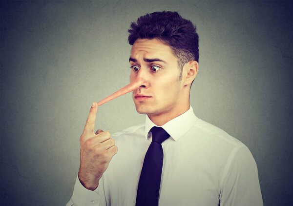 Worried young business man with long nose. Liar concept. 