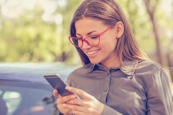 Junge Frau, die an einem Herbsttag im Freien mit dem Smartphone SMS schreibt — Stockfoto