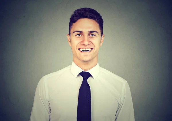 Knappe jonge man die lacht op grijze achtergrond — Stockfoto