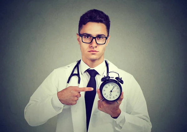 Серьезный врач указывает на часы — стоковое фото