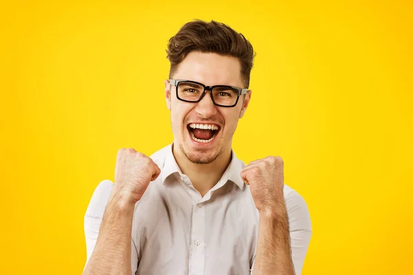 Junger Mann mit Brille hält die Fäuste in die Höhe und feiert Erfolg — Stockfoto