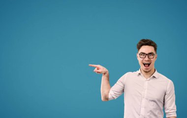 Mutlu bir şekilde uzağa işaret gözlüklü genç hipster adam