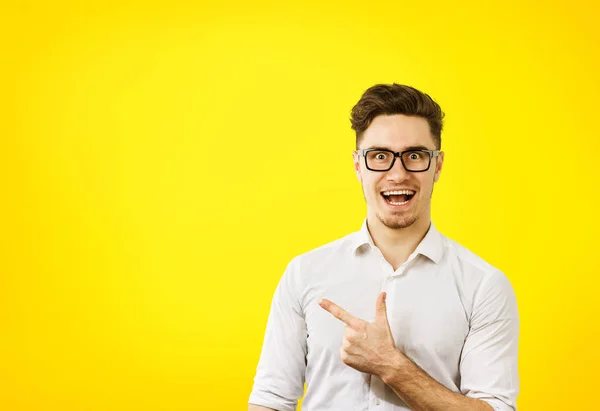 Joven hipster hombre en gafas apuntando felizmente lejos — Foto de Stock