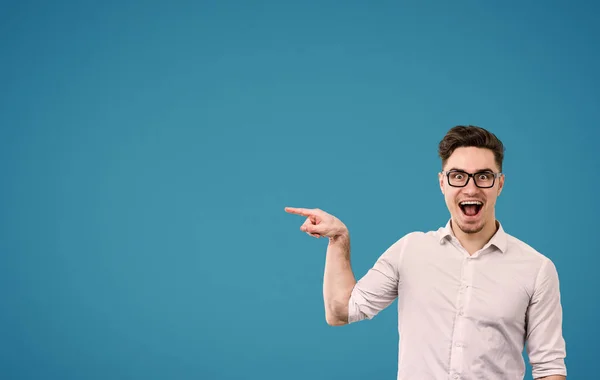 Joven hipster hombre en gafas apuntando felizmente lejos — Foto de Stock