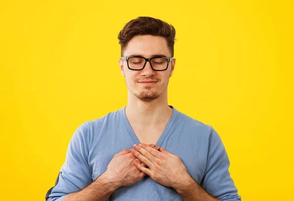 El hombre fiel con los ojos cerrados mantiene las manos en el pecho cerca del corazón, muestra bondad — Foto de Stock