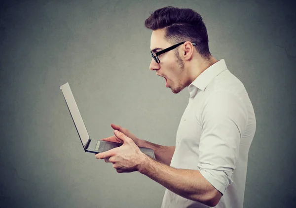 Geschockter Mann liest Nachrichten auf Laptop — Stockfoto