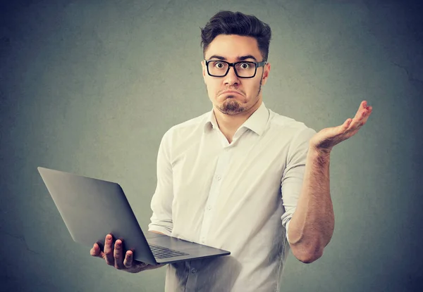 Perplexed young man with laptop — Stock Photo, Image