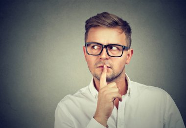 Suspicious man holding finger on lips clipart