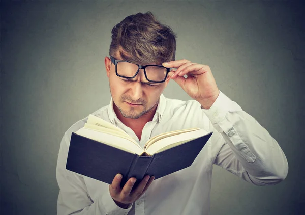 Hombre frunciendo el ceño que tiene problemas con la lectura —  Fotos de Stock