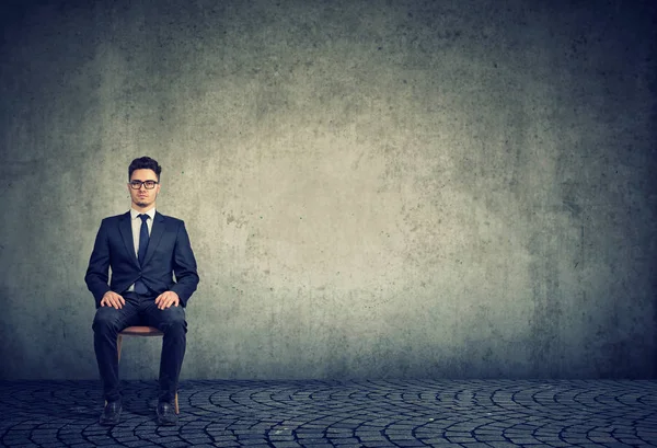 Hombre de negocios serio sentado sobre fondo gris —  Fotos de Stock