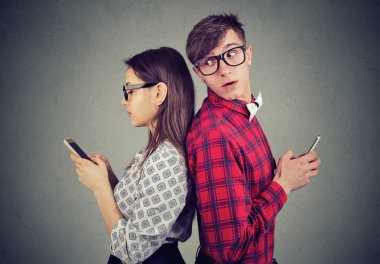 Kıskanç adam ne yapıyor görmek için çalışırken kız telefonu, omzunun üzerinden bakarak manifatura 