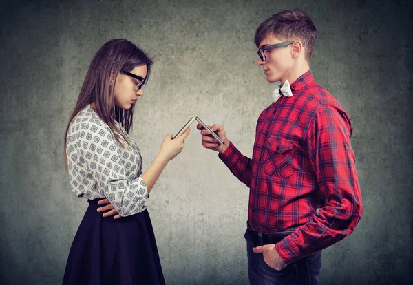 Pareja que utiliza teléfonos inteligentes totalmente absortos en la vida en línea, no hablar entre sí, frente a frente . — Foto de Stock