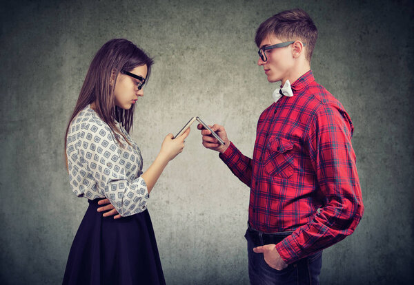 Пара, использующая смартфоны полностью поглощенные онлайн жизнью, не разговаривающие друг с другом, лицом друг к другу
. 