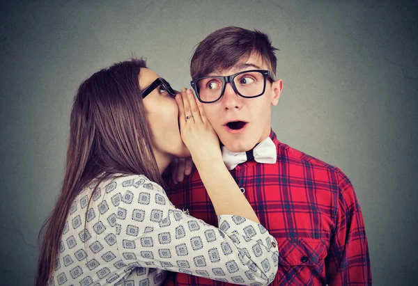 Mujer contando susurros de chismes secretos en el oído a un hombre sorprendido — Foto de Stock