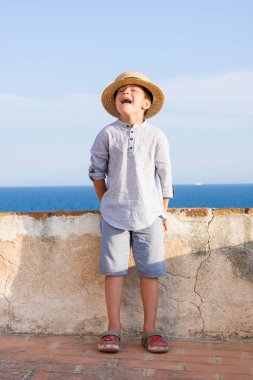 Hasır Şapkalı çocuk denizle gülümsüyor