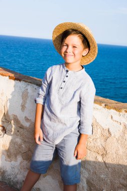 Hasır Şapkalı çocuk denizle gülümsüyor