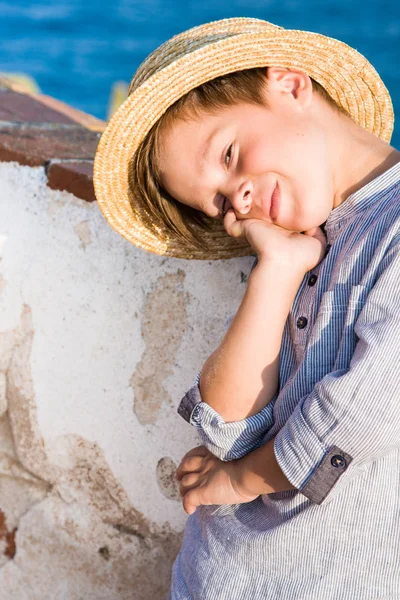 Boy in straw hat smiles against sea — Stock Photo, Image