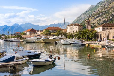 Kotor, Karadağ - 24 Haziran 2015: Denizde dağlar ve eski şehir ile gün batımında tekne