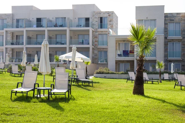 Paphos, Chypre - 20 juillet 2017 : Palm beach avec chaises longues vides contre Amphora Hotel & Suitel. Situé sur l'emplacement idyllique en bord de mer de l'ancienne cave SODAP — Photo