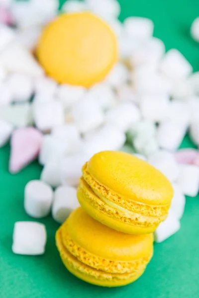 Yellow macaroons and marshmallow on green — Stock Photo, Image