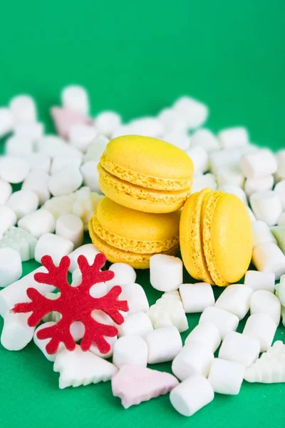 Yellow macaroons, marshmallow and red flake on green — Stock Photo, Image