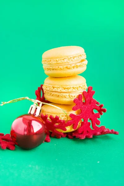 Macaroons amarelos com decorações de ano novo no fundo verde — Fotografia de Stock