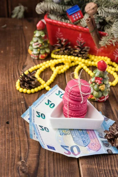 Розовые макароны и двадцать евро с рождественскими украшениями на фоне дерева — стоковое фото