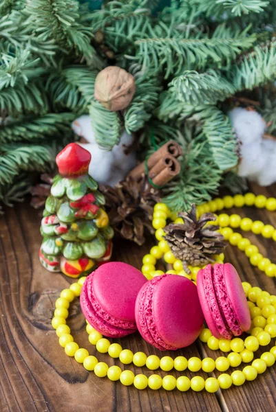 Rosa Makronen mit Weihnachtsdekoration auf holzfarbenem Hintergrund — Stockfoto