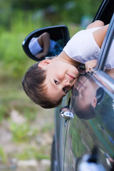 Boy looks out of car window and smiles — Stock Photo, Image