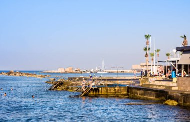 Paphos - 12 Temmuz 2017: Turist yüzmek üzerinde Poseidonos Ave Pafos, Kıbrıs için belediye hamamları yakınlarında küçük kayalık plaj