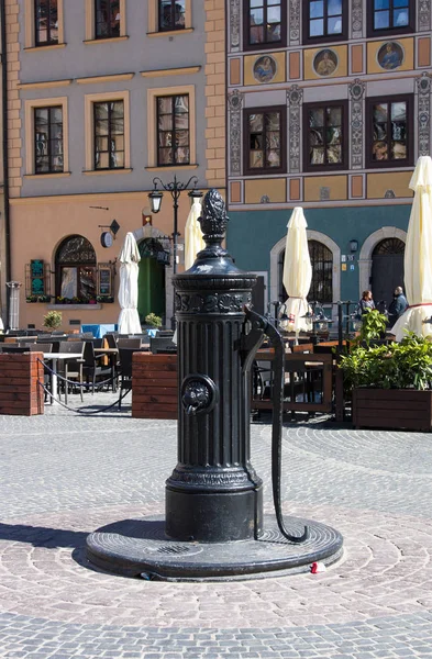 Varsavia, Polonia - 23 aprile 2017: Antica colonna d'acqua nella Piazza del Mercato della Città Vecchia contro palazzi e ristoranti — Foto Stock