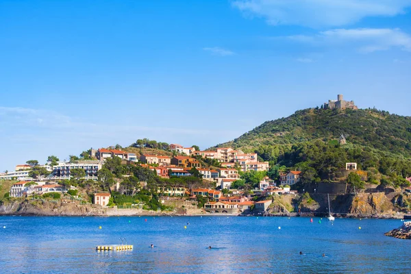 COLLIOURE, FRANCE - JULY 5, 2016: Beach hotels in Collioure village with a windmill at the top of the hill, Roussillon, Vermilion coast, Pyrenees Orientales, France — Stock Photo, Image