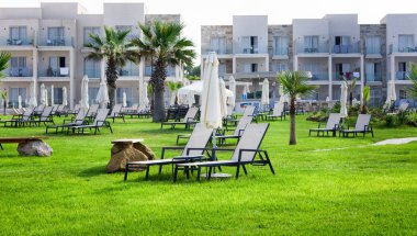 Paphos, Kıbrıs - 20 Temmuz 2017: Palm beach Amphora otel ve Suitel karşı boş şezlong ile. Eski Sodap Winery sahil pastoral konumunu ayarlama