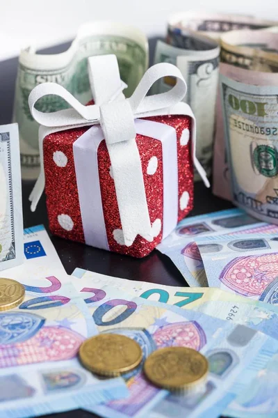 Red toy gift, dollars and euro on black background — Stock Photo, Image