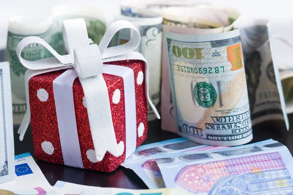 Red toy gift, dollars and euro on black background — Stock Photo, Image