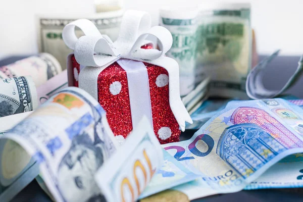 Red toy gift, dollars and euro on black background — Stock Photo, Image