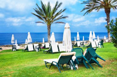 Paphos, Kıbrıs - 20 Temmuz 2017: Palm beach Constantinou Bros Athena Beach Hotel karşı boş şezlong ile. Otel tam olarak 10/11 kışında yenilenmiştir