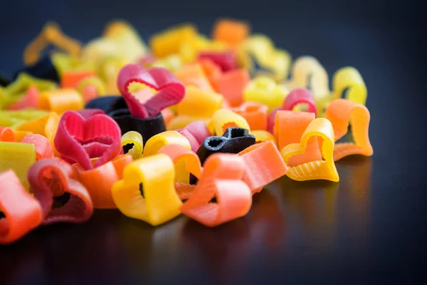 Heart-shaped pasta on black table. — Stock Photo, Image