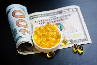 Balık yağı ve siyah arka plan üzerine dolar kapsül