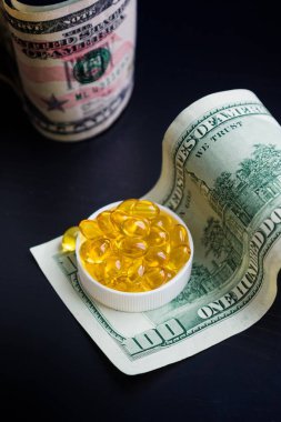 Balık yağı ve siyah arka plan üzerine dolar kapsül