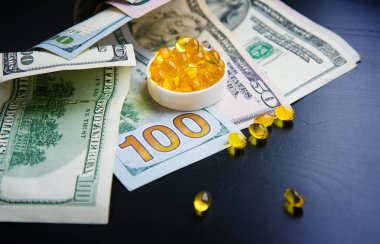 Balık yağı ve siyah arka plan üzerine dolar kapsül