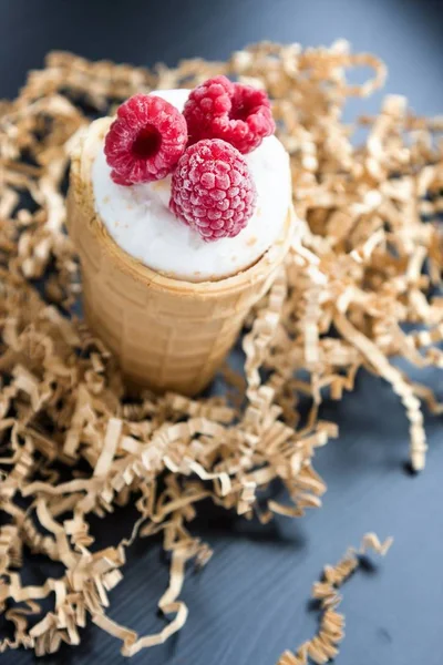 Ice cream with raspberry in waffle cone on wood — Stock Photo, Image