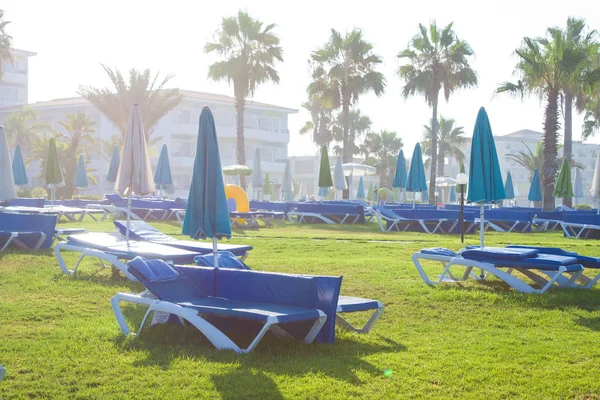 Paphos, Chypre - 20 juillet 2017 : Palm beach avec chaises longues vides contre le Constantinou Bros Athena Beach Hotel. L'hôtel a été entièrement rénové en hiver 10 / 11 — Photo