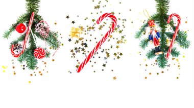 Noel süsleri. Çizgili şekerli kompozisyon kolajı, kırmızı elma, koni, altın hediye, çan, ahşap fındıkkıran ve beyaz arka planda konfeti. Düz yatıyordu. Yeni yıl ve Noel havası