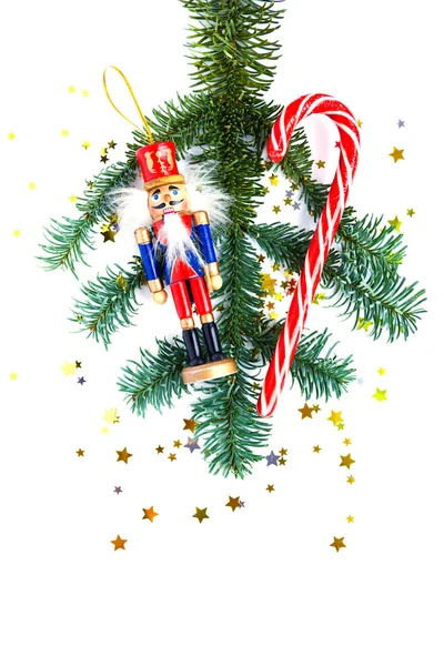Kerstversiering en boomtak op witte achtergrond. Gestreept snoep, houten notenkraker, confetti. Vlakke plaat. — Stockfoto