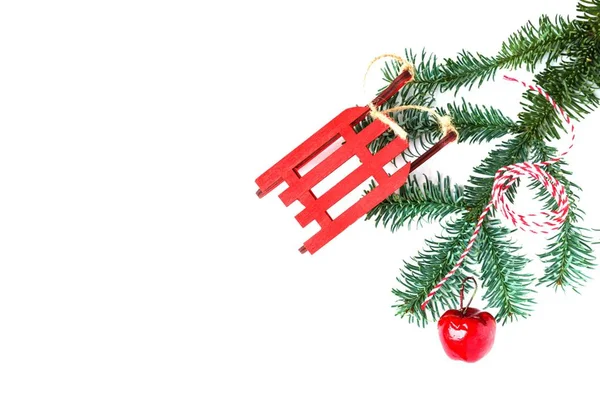 Decoraciones navideñas y rama de árbol sobre fondo blanco. Copiar espacio. trineo de juguete de Año Nuevo, manzana roja e hilo rayado —  Fotos de Stock