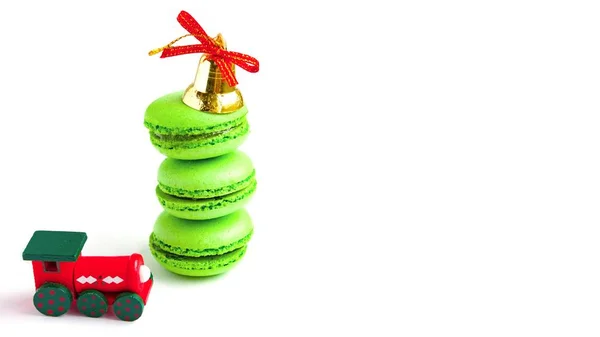 Macarones verdes con campana de navidad dorada y tren de juguete de año nuevo en blanco —  Fotos de Stock